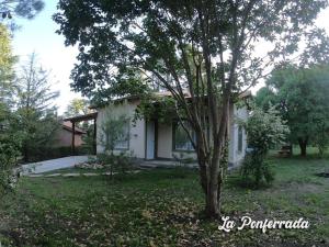 a small white house with a tree in the yard at La ponferrada in Villa Ventana