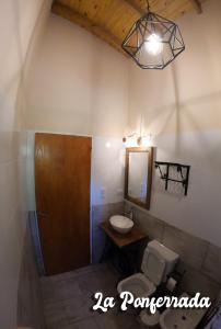 een badkamer met een wastafel, een toilet en een spiegel bij La ponferrada in Villa Ventana