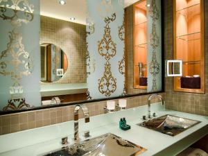 a bathroom with a sink and two mirrors at Sofitel Legend The Grand Amsterdam in Amsterdam
