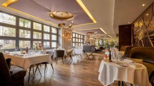 a restaurant with white tables and chairs and windows at Sofitel Legend The Grand Amsterdam in Amsterdam