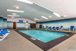 a swimming pool in a gym with blue chairs at SureStay Plus Hotel by Best Western Salmon Arm in Salmon Arm