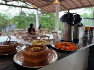 a counter with some pastries and fruit on plates at Pousada Pedras Quentes in Lençóis +38 photos