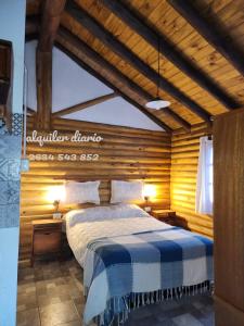 um quarto com uma cama num quarto de madeira em La margarita em Potrerillos