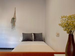 Bett in einem Zimmer mit einer Blumenvase in der Unterkunft Apartamento estación de Portbou in Portbou