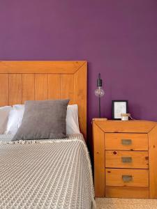a bedroom with a bed and a dresser and purple wall at Apartamento estación de Portbou in Portbou