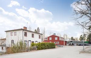 a white house and a red building on a street at Stunning Apartment In Hlleforsns With Wifi And 2 Bedrooms in Hälleforsnäs