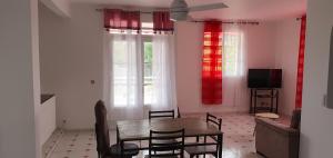 een woonkamer met een tafel en stoelen en een televisie bij Villa HAVA in Anse-Bertrand