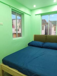 a bedroom with a bed and two windows at Camella Homes in Tagbilaran City