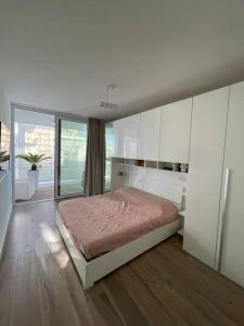 a white bedroom with a bed and a large window at Palm beach appartment 80 mt dal mare e comodo per Venezia in Lido di Jesolo
