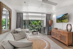 a living room with a white couch and a large window at Belle Escapes Drift Beachfront Resort Suite 3409 in Palm Cove