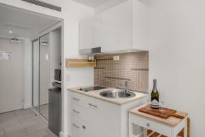 a kitchen with a sink and a bottle of wine at Belle Escapes Drift Beachfront Resort Suite 3409 in Palm Cove
