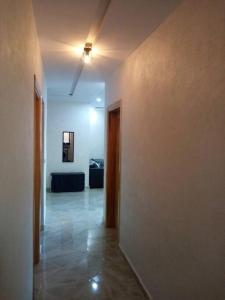 um quarto vazio com um corredor com uma parede branca em Chez Franck em Saidia 