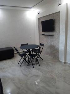 a dining room with a table and chairs and a tv at Chez Franck in Saïdia