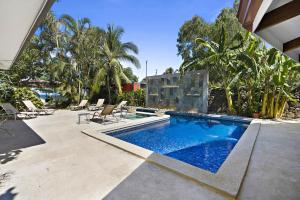 a swimming pool with chairs and a house at Playa Potrero - beachfront Villa, big private pool - Casa Bella Catalina in Potrero