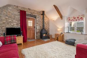 a living room with a stone wall and a fireplace at Summerhill Cottage in Mathry