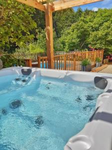 bañera de hidromasaje en un patio trasero con pérgola de madera en Villa Saint Kirio - piscine et spa en Morlaix