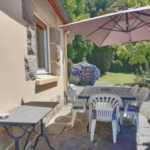 una mesa, sillas y una sombrilla en el patio en Villa Saint Kirio - piscine et spa en Morlaix