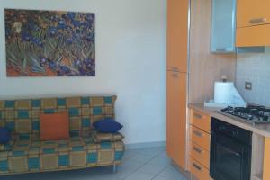 una cocina con sofá y una pintura en la pared en Appartamento a 200MT da "La Pelosa" en Stintino