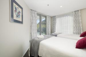 two beds in a room with a window at Oceanside Apartment with Iconic Views in Mount Maunganui