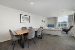 a dining room with a table and chairs and a couch at Oceanside Apartment with Iconic Views in Mount Maunganui