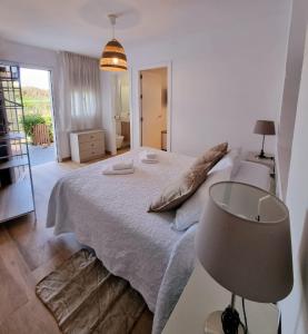 a white bedroom with a bed and a lamp at Hotel-Apart CORTIJO LAS PIÑAS in Tarifa