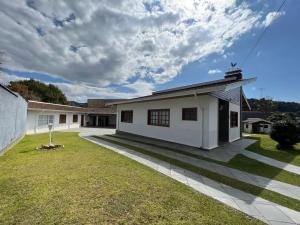 a large white house with a grass yard at Recanto do Aconchego in Campos do Jordão