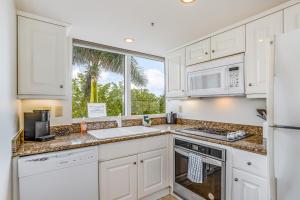 cocina con armarios blancos y ventana grande en Marco Beach Ocean Resort 614, en Marco Island