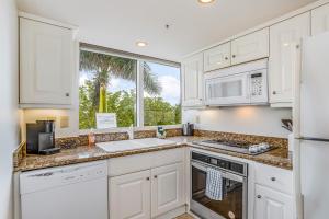 a kitchen with white cabinets and a large window at Marco Beach Ocean Resort 614 in Marco Island