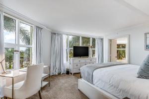 a white bedroom with a bed and a tv and windows at Marco Beach Ocean Resort 614 in Marco Island