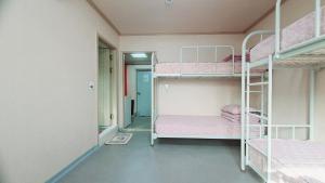 a room with two bunk beds with pink sheets at Happy Garden Guesthouse in Seoul