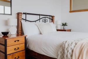 - une chambre avec un lit blanc et une commode en bois dans l'établissement OceanFront - Absolute Waterfront, à Bicheno
