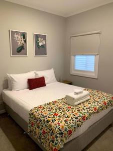 um quarto com uma cama com um cobertor e uma janela em Kiama Tea House em Bicheno