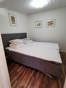 een bed in een kamer met witte muren en houten vloeren bij Tofta Konstgalleri-Hel Lägenhet 70kvm in Varberg