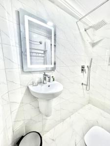 uma casa de banho branca com um lavatório e um espelho em Blaze by Treston Grand Apartment, Maitama em Abuja