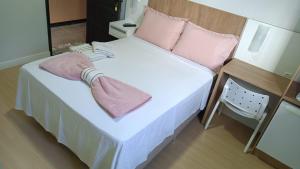 a small bed with pink pillows on top of it at Pousada Emilly in Joinville