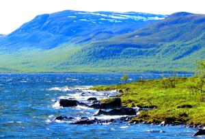 a body of water with mountains in the background at Haltinmaa Cottages in Kilpisjärvi