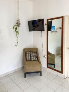 a chair in a room with a mirror and a tv at Cómodo y bonito estudio en Cozumel in Cozumel