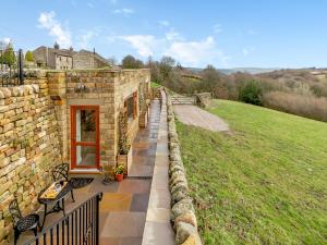 a stone building with a walkway next to a field at The Burrow in Pateley Bridge