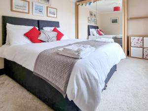 a bedroom with a large bed with red and white pillows at Cobweb Cottage in Ludham