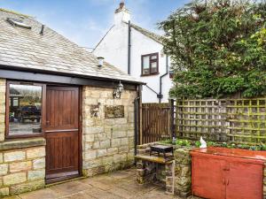 a stone house with a wooden door and a fence at Priory Barn in Burscough