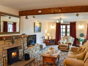 a living room with a fireplace and a couch and chairs at Priory Barn in Burscough