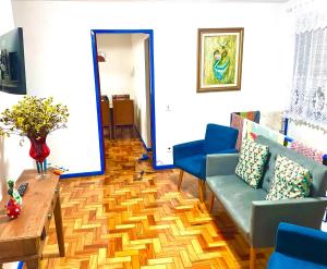 a living room with a couch and a table and blue chairs at Casa charmosa no Centro Histórico com garagem in Ouro Preto