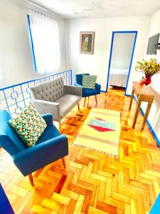 a living room with blue chairs and a wooden floor at Casa charmosa no Centro Histórico com garagem in Ouro Preto