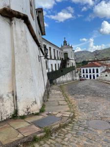 a cobblestone street in front of a white building at Casa charmosa no Centro Histórico com garagem in Ouro Preto