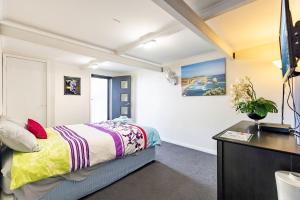 ein Schlafzimmer mit einem Bett und einem Schreibtisch in einem Zimmer in der Unterkunft Away Nelson Bay, 29 Wollomi Ave - Spacious family home with water views, pet friendly, Wifi & aircon in Nelson Bay
