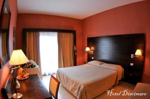 カーヴァ・デ・ティッレーニにあるHotel Diecimareのベッド、デスク、テーブルが備わるホテルルームです。