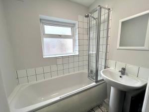 a white bathroom with a sink and a tub and a window at 4 bedroom home 10 mins to city in Gateshead
