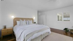 a white bedroom with a large bed and a window at Malolo in Yamba