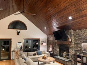 a living room with a couch and a stone fireplace at Catskills Cabin: Hot Tub, Firepit, WFH, Ski, Games in Lexington