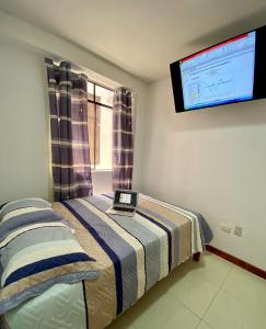 a bedroom with a bed with a tv on the wall at Hostal Venus - Nueva Imagen in Huacho